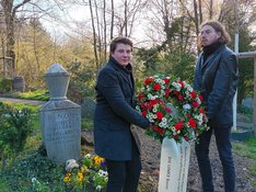 Andreas Darstar (Kreissprecher) und Hendrik Schlüter (Redner) präsentieren am Grab von Otto Renois in Poppelsdorf einen Kranz zum Gedenken an seinen 90. Todestag.