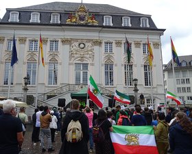 Teilnehmende der Kundgebung von hintern vor dem Alten Rathaus auf dem Bonner Marktplatz mit zahlreichen Iran-Flaggen