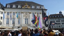 Der Demozug ist auf dem Marktplatz angekommen; im Hintergrnd das alte Rathaus.  Rechts ist ein Banner mit der Aufschrift "Bonn bleibt bunt" zu sehen.